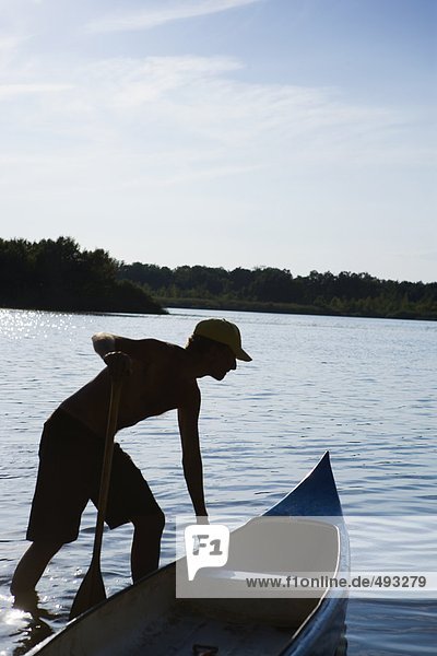 Silhouette von einem Mann mit einem Kanu.