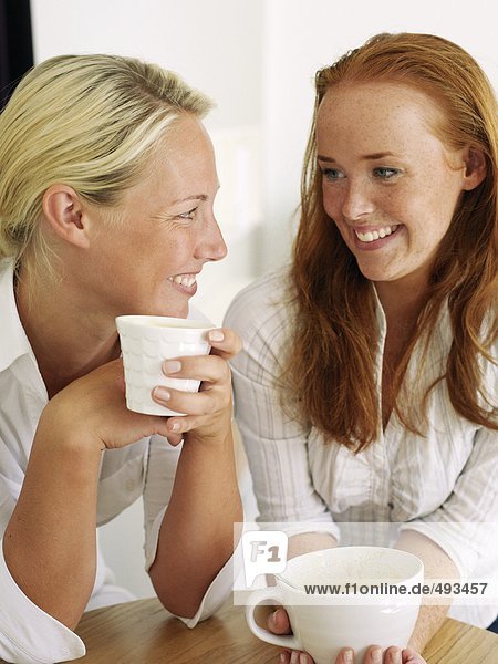 Two young women drinking coffee.