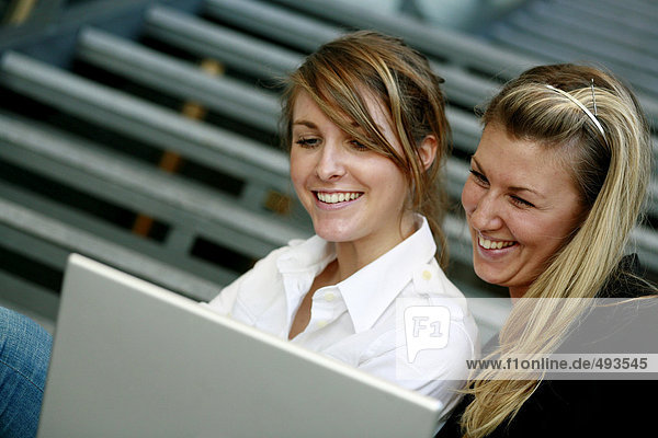 Zwei lächelnd Frauen und einen Laptop.
