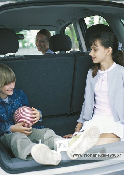 Children sitting in car trunk
