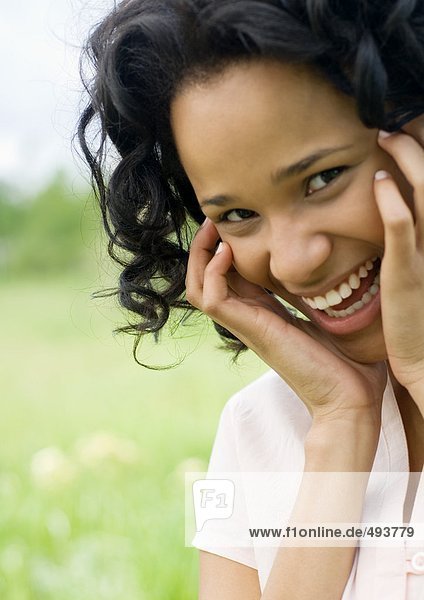 Young woman smiling with hands on side of face