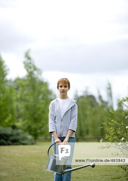 Girl standing in yard with watering can