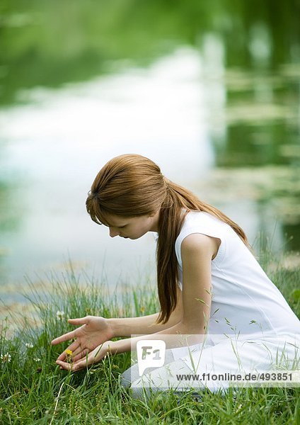 Mädchen kniend im Gras mit schalenförmigen Händen