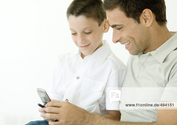 Mann und Sohn schauen gemeinsam aufs Handy