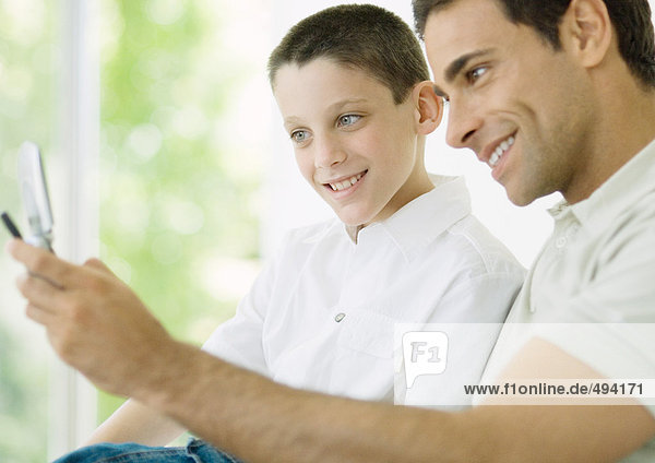 Mann und Sohn schauen auf Handy