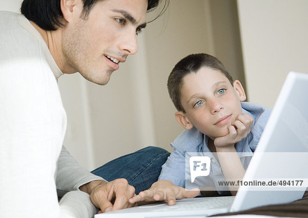 Man and boy using laptop together