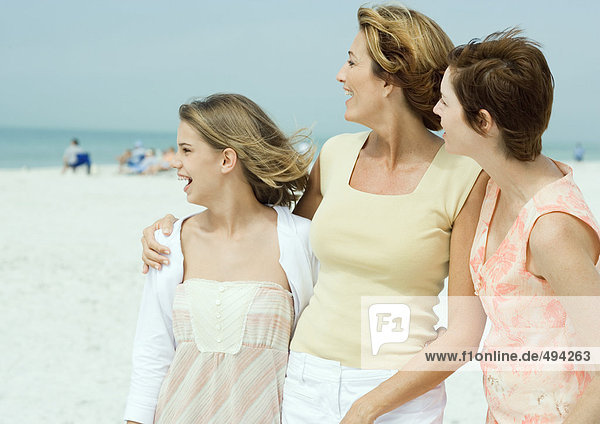Mother with teenage daughter and friend on beach  looking toward distance