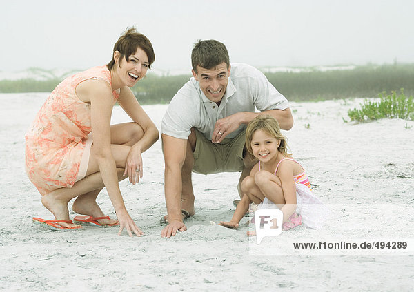 Familie am Strand  spielen im Sand  lächeln vor der Kamera
