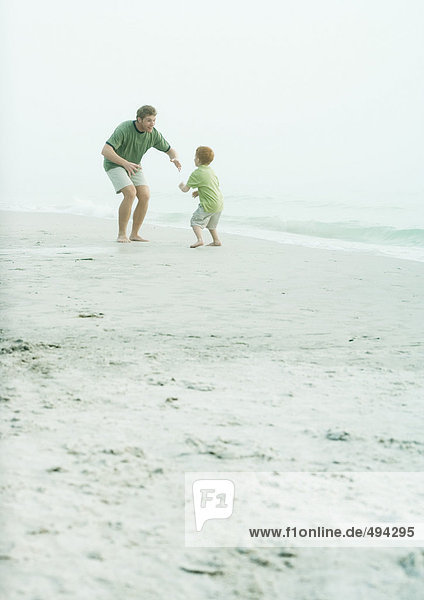 Vater und Sohn spielen am Strand.