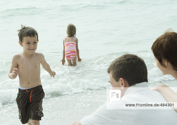 Family at the beach  boy running out of water towards parents