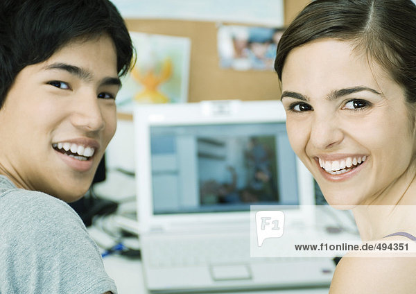 Junges Paar lächelt  Laptop im Hintergrund