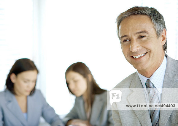 Businessman smiling  colleagues in background