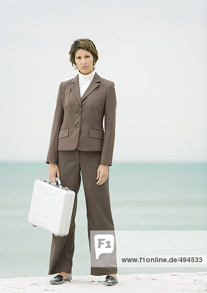 Geschäftsfrau am Strand stehend mit Aktentasche