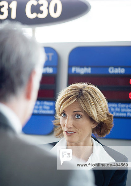 Flugbegleiterin im Gespräch mit dem Passagier am Check-in-Schalter