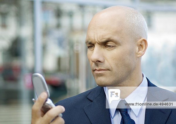 Businessman looking at cell phone  furrowing brow