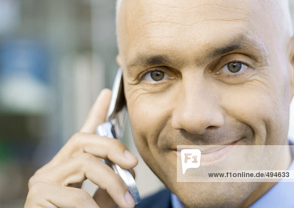 Businessman using cell phone  smiling