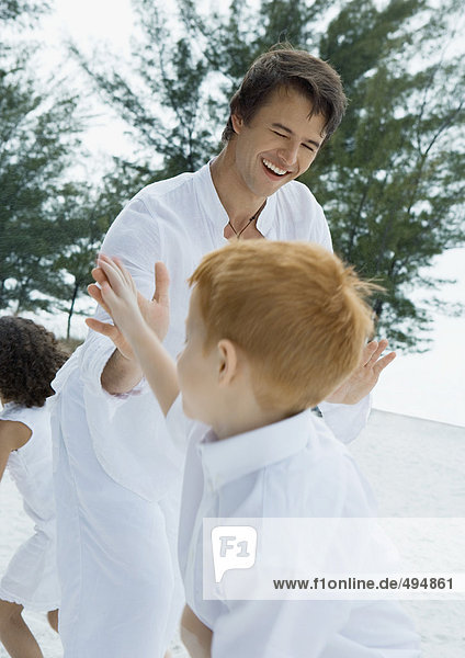 Man and boy hitting hands together during beach celebration