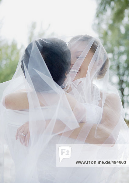 Bride and groom embracing under veil