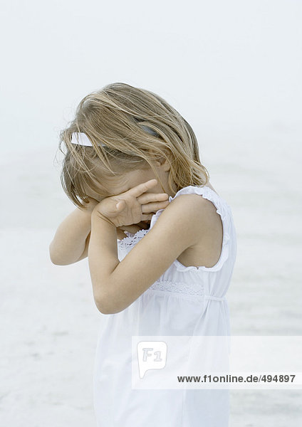 Girl covering face on beach