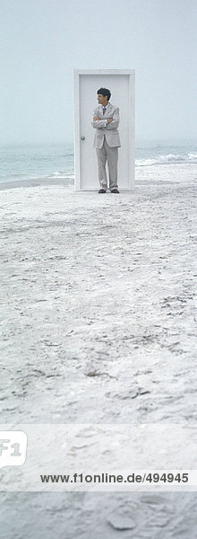 On beach  businessman standing in front of closed door
