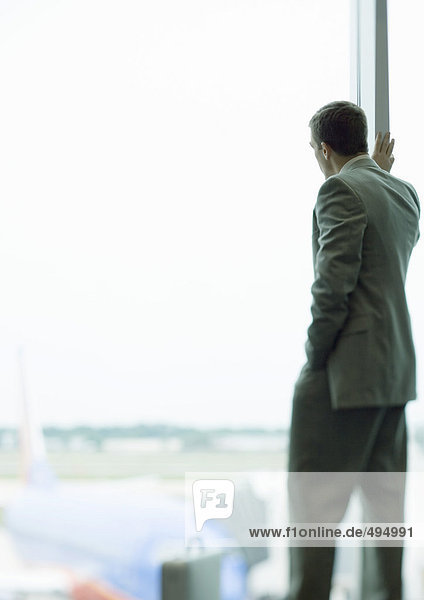 Mann steht am Fenster im Flughafen