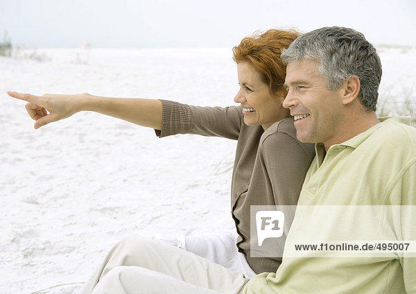 Erwachsenes Paar am Strand sitzend  Seitenansicht
