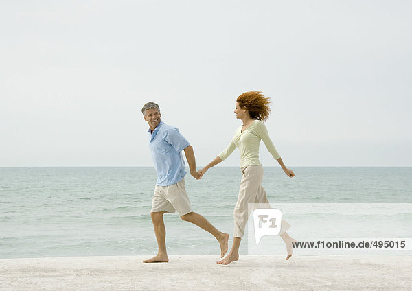 Erwachsene Paare  die am Strand laufen