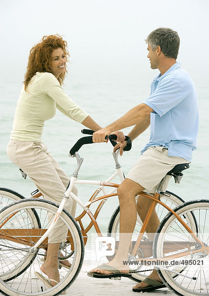 Couple face to face on bikes  on beach