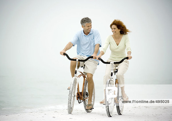 Couple riding bikes on beach