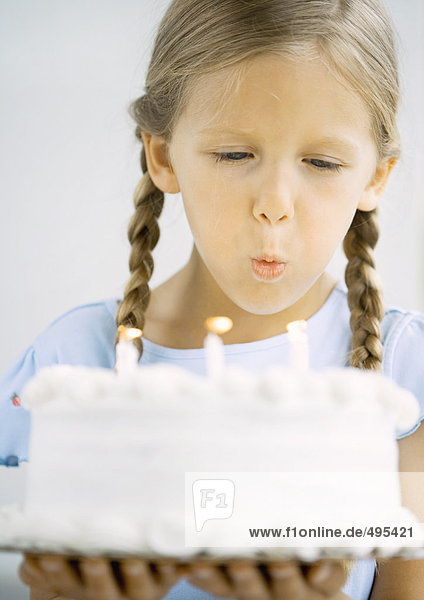 Kleines Mädchen mit Geburtstagskuchen  Kerzen ausblasen