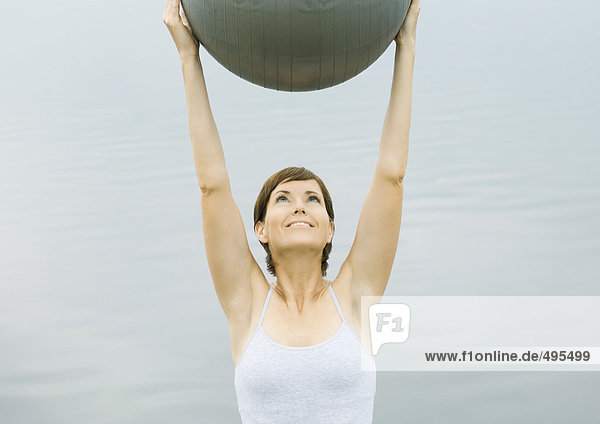 Woman exercising with fitness ball  next to lake