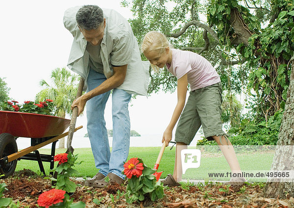 Mann und Mädchen pflanzen Blumen im Hof