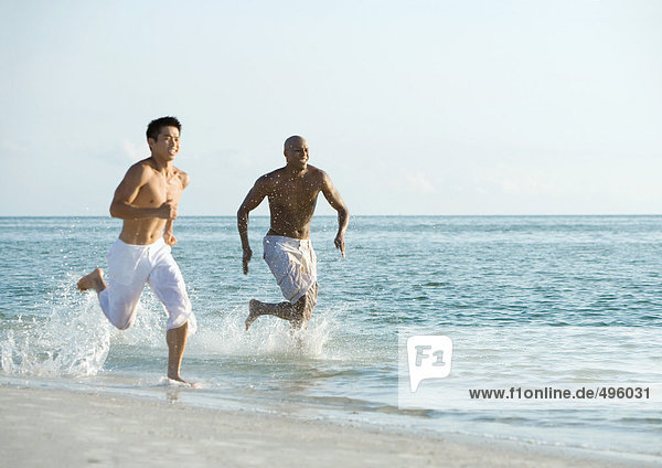 Two men running in surf