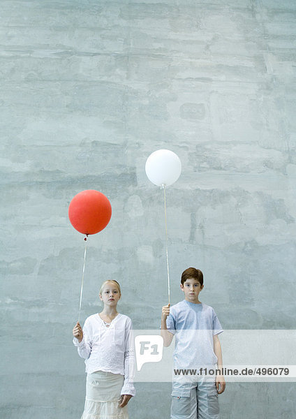 Zwei Kinder halten Luftballons