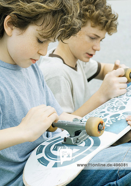 Zwei Jungen  die auf Skateboard-Räder schauen