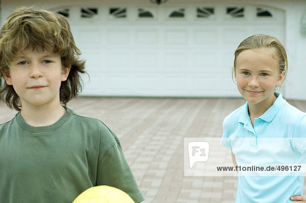 Boy and girl standing in front of driveway  smiling