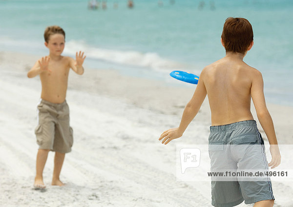 Boys playing frisbee on beach