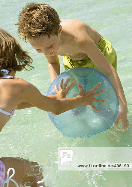 Junge und Mädchen spielen mit dem Ball im Meer