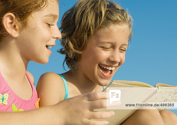 Mädchen im Badeanzug lesen gemeinsam Buch