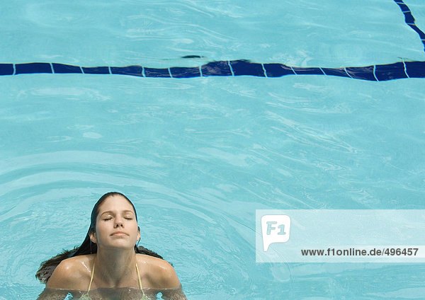 Frau im Pool stehend  Kopf hinten und Augen geschlossen  Frontansicht