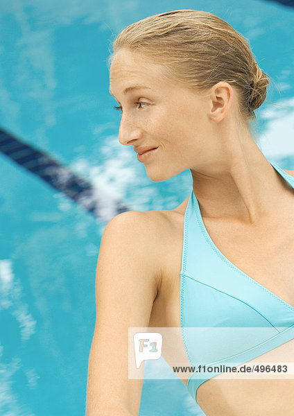 Frau im Bikini sitzend am Pool