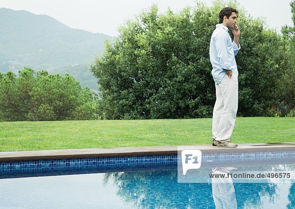 Mann mit Handy neben dem Pool
