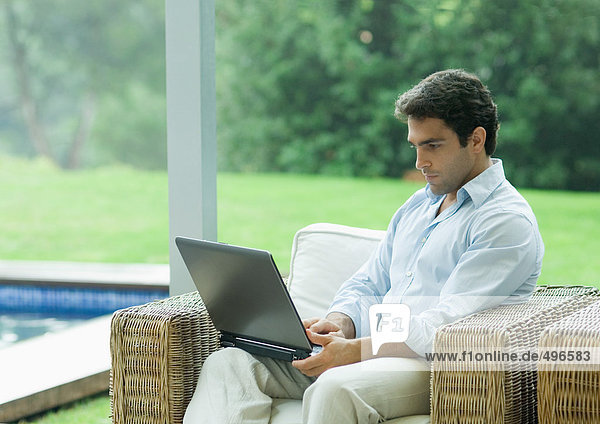 Mann mit Laptop im Freien im Sessel