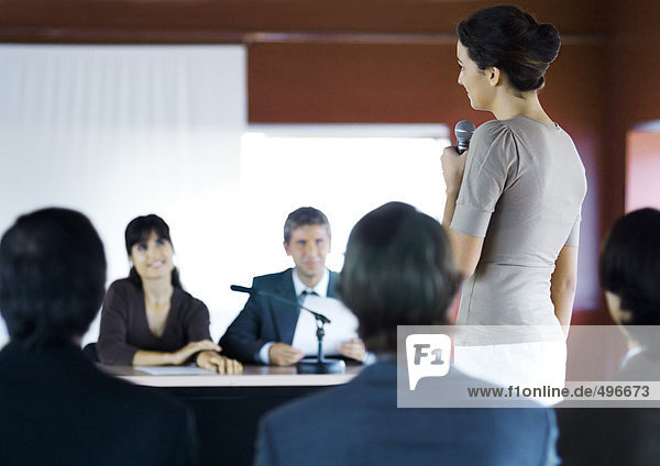 Businesspeople in seminar  one woman standing with microphone