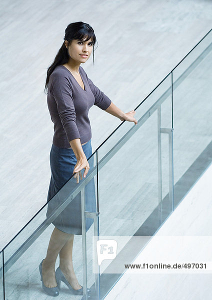 Woman standing with hands on glass guard rail  full length portrait