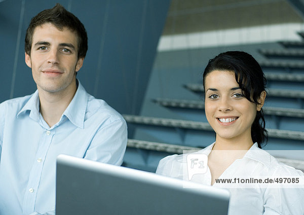 Zwei Kollegen auf der Treppe  mit Laptop  lächelnd