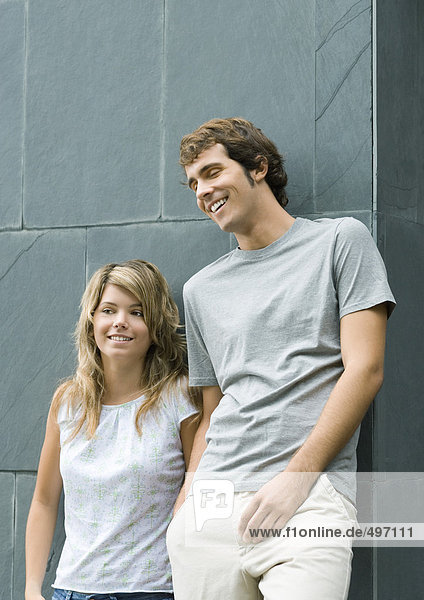 Junger Mann und Frau  die sich an die Wand lehnen  lächelnd