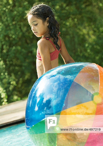 Mädchen im Pool stehend  mit Strandball