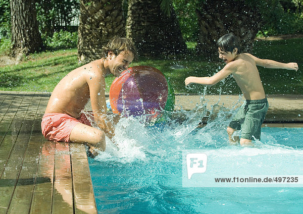 Father and son splashing in swimming pool