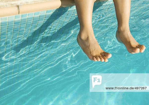 Füße baumeln über dem Schwimmbad